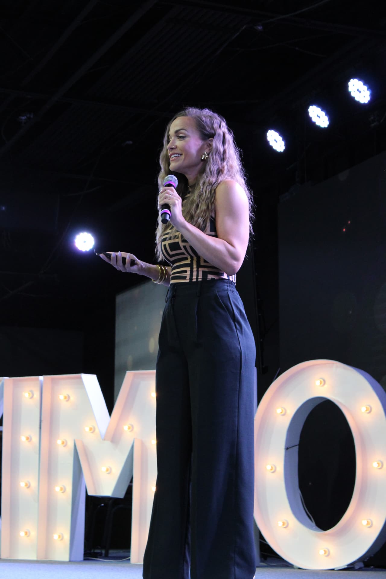 Molly Gomez speaking on stage at a live Aligned & Assigned event