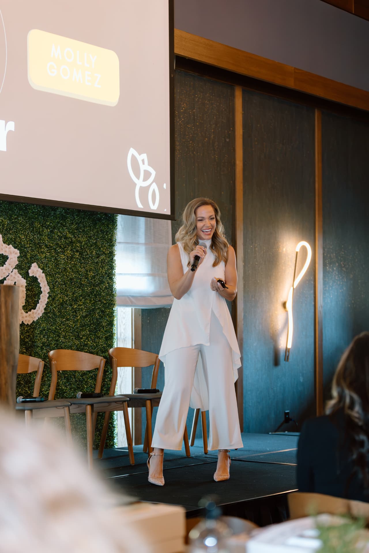 Molly Gomez speaking on stage at a women's leadership event