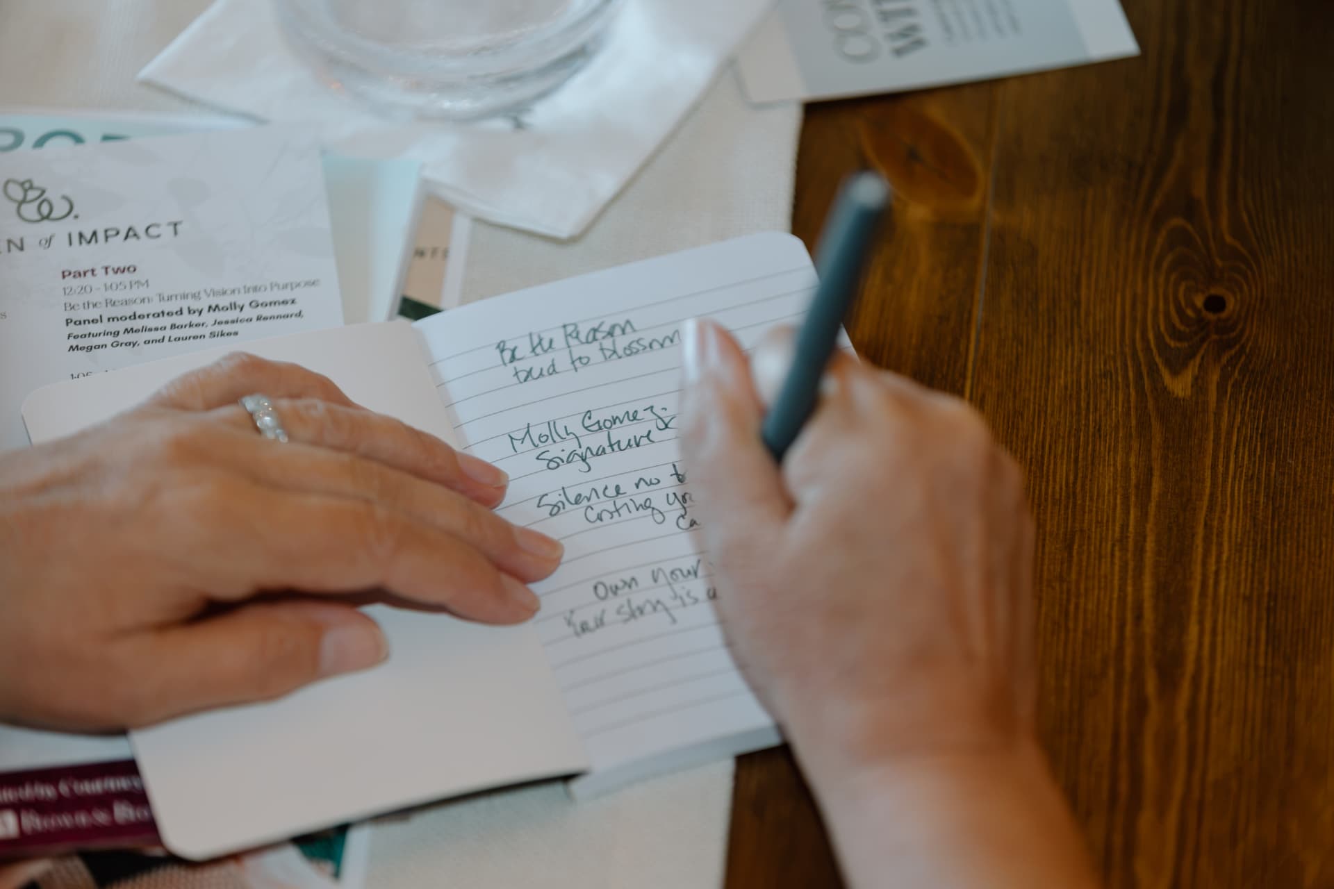 A woman's hand writing notes on Signature Storytelling during a live teaching session